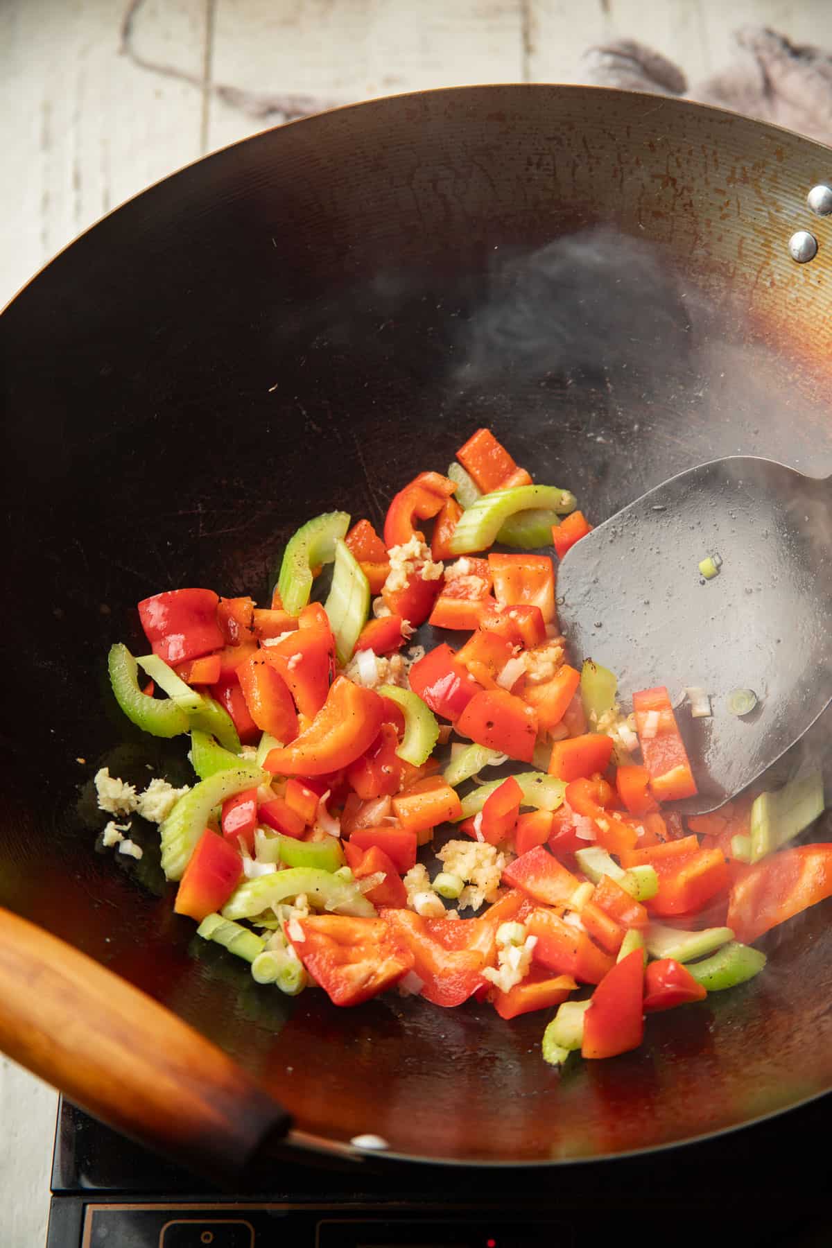Vegetables and aromatics cooking in a wok.