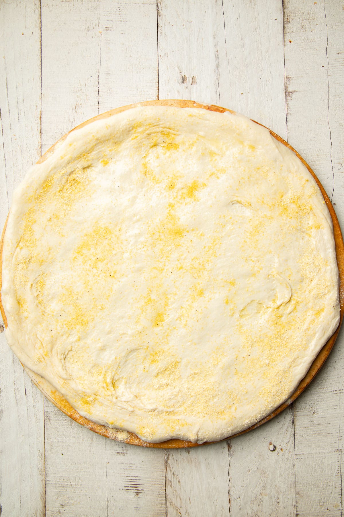 Unbaked pizza crust on a pizza stone.
