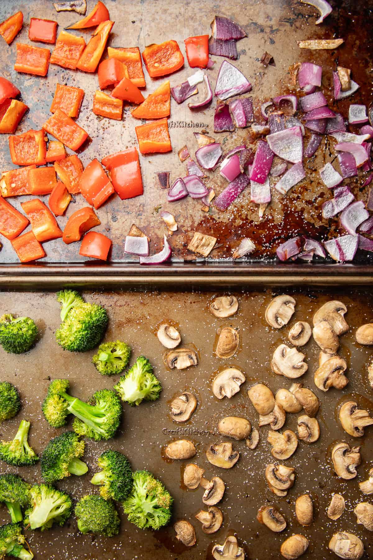 Roasted bell peppers, red onion, broccoli florets and mushroom slices on two baking sheets.