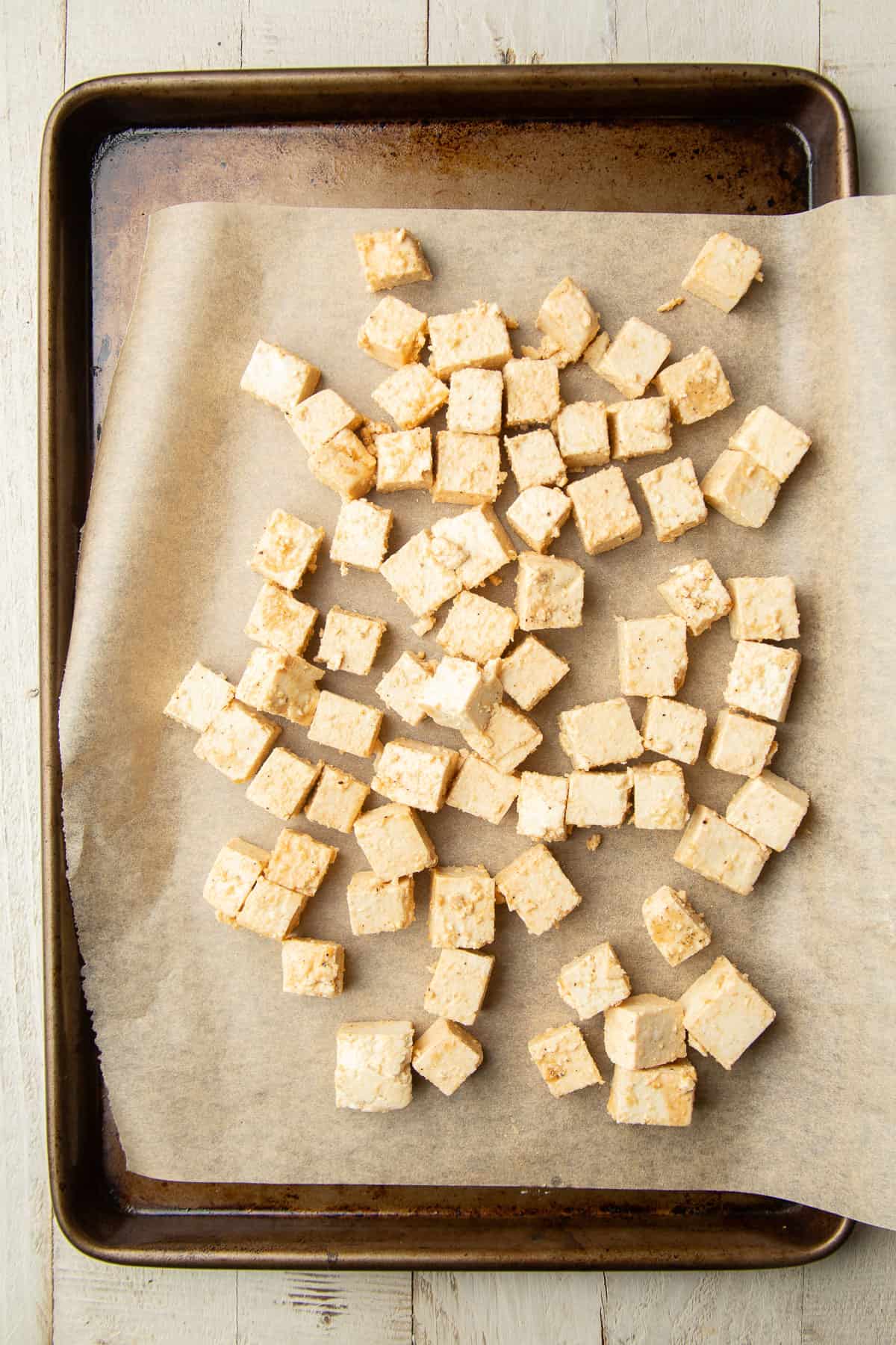 Tofu cubes on a parchment paper-lined baking sheet.