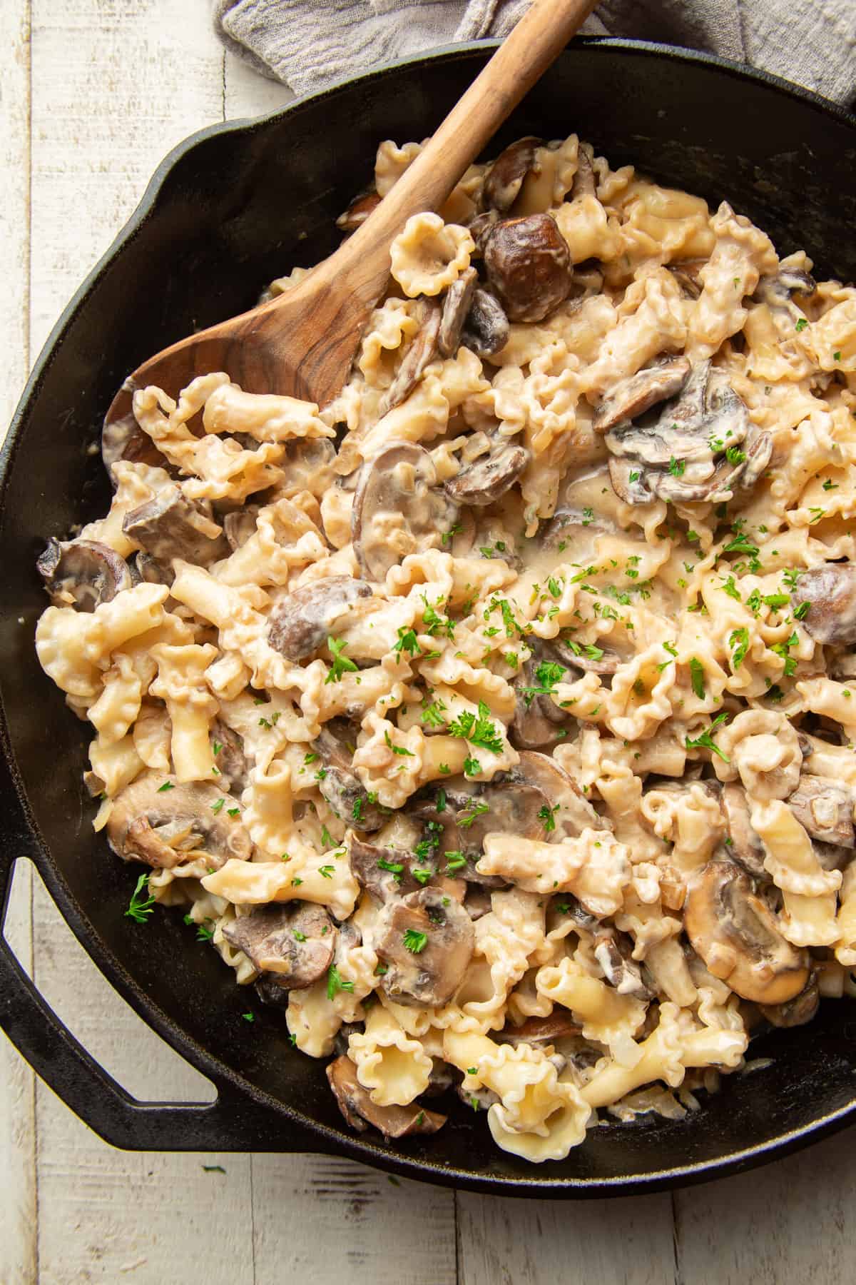 Skillet filled with Vegan Mushroom Stroganoff with a wooden spoon.