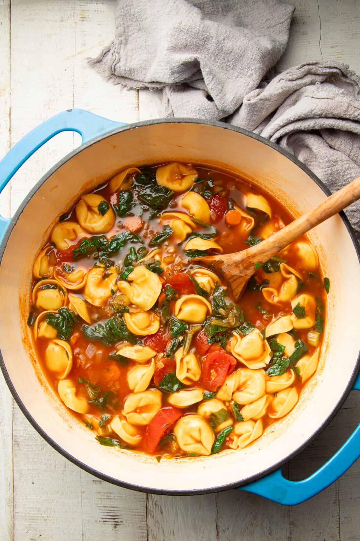 Pot of Vegan Tortellini Soup with a wooden spoon.