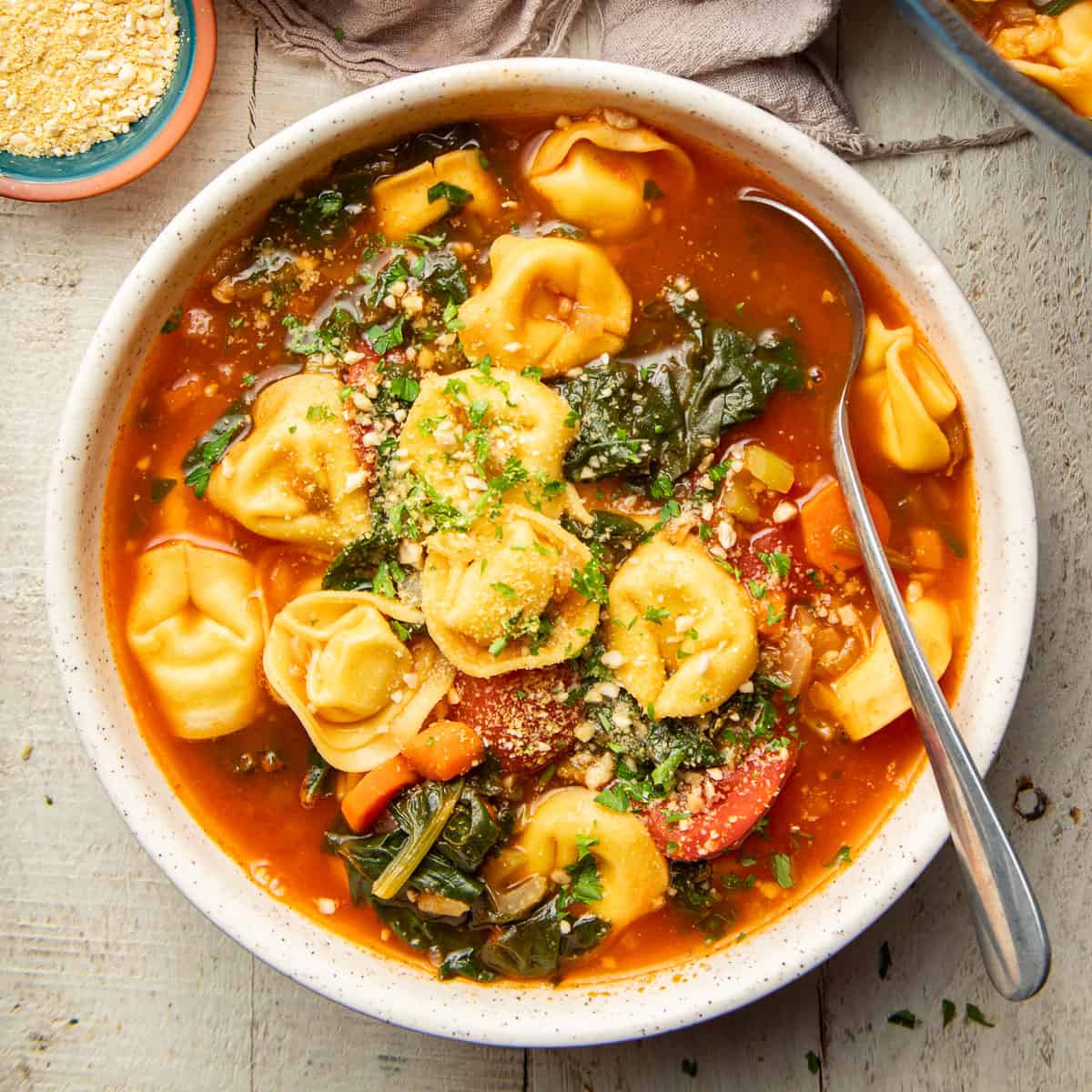 Bowl of Vegan Tortellini Soup with a spoon.
