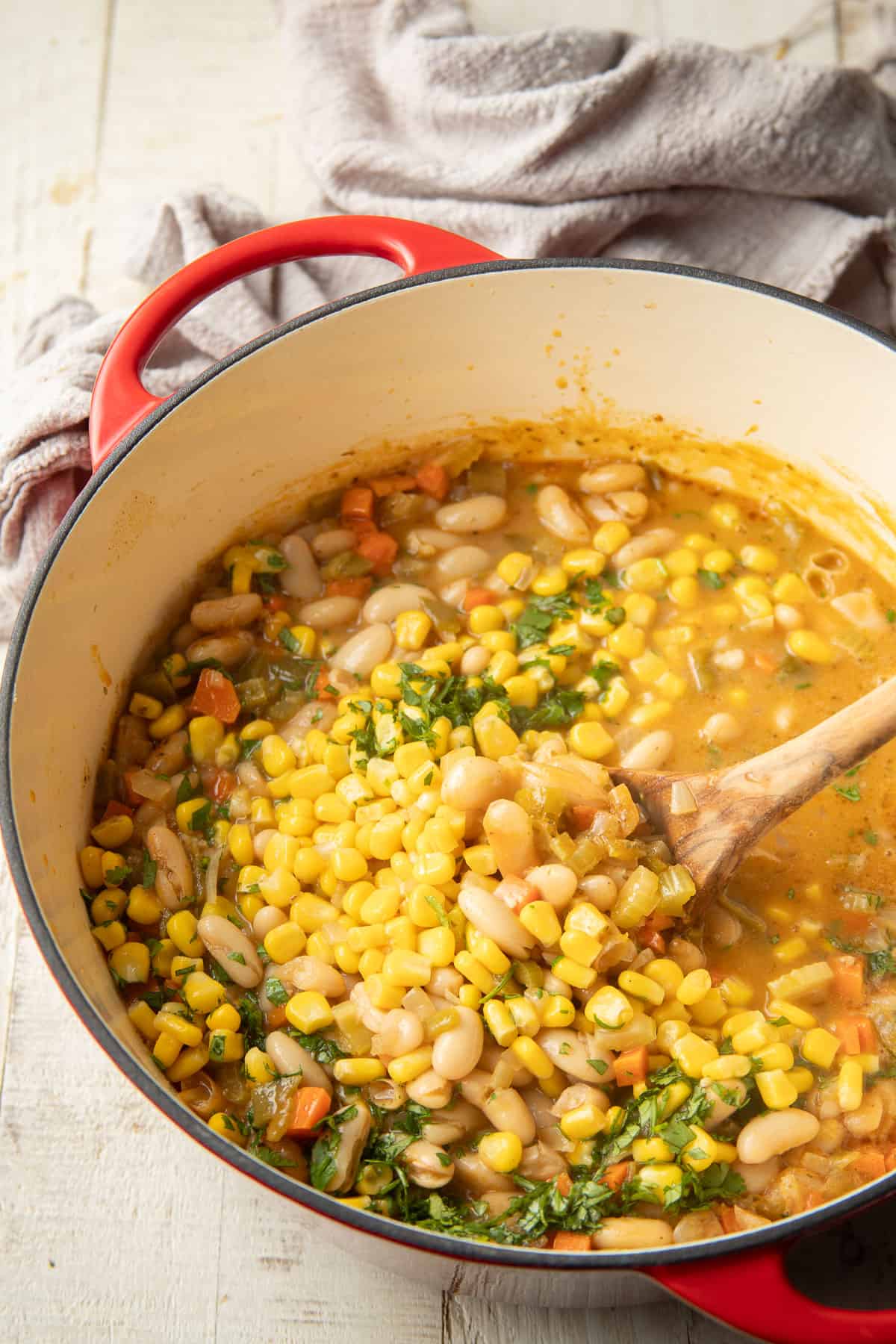 Corn being stirred into a pot of Vegan White Bean Chili.