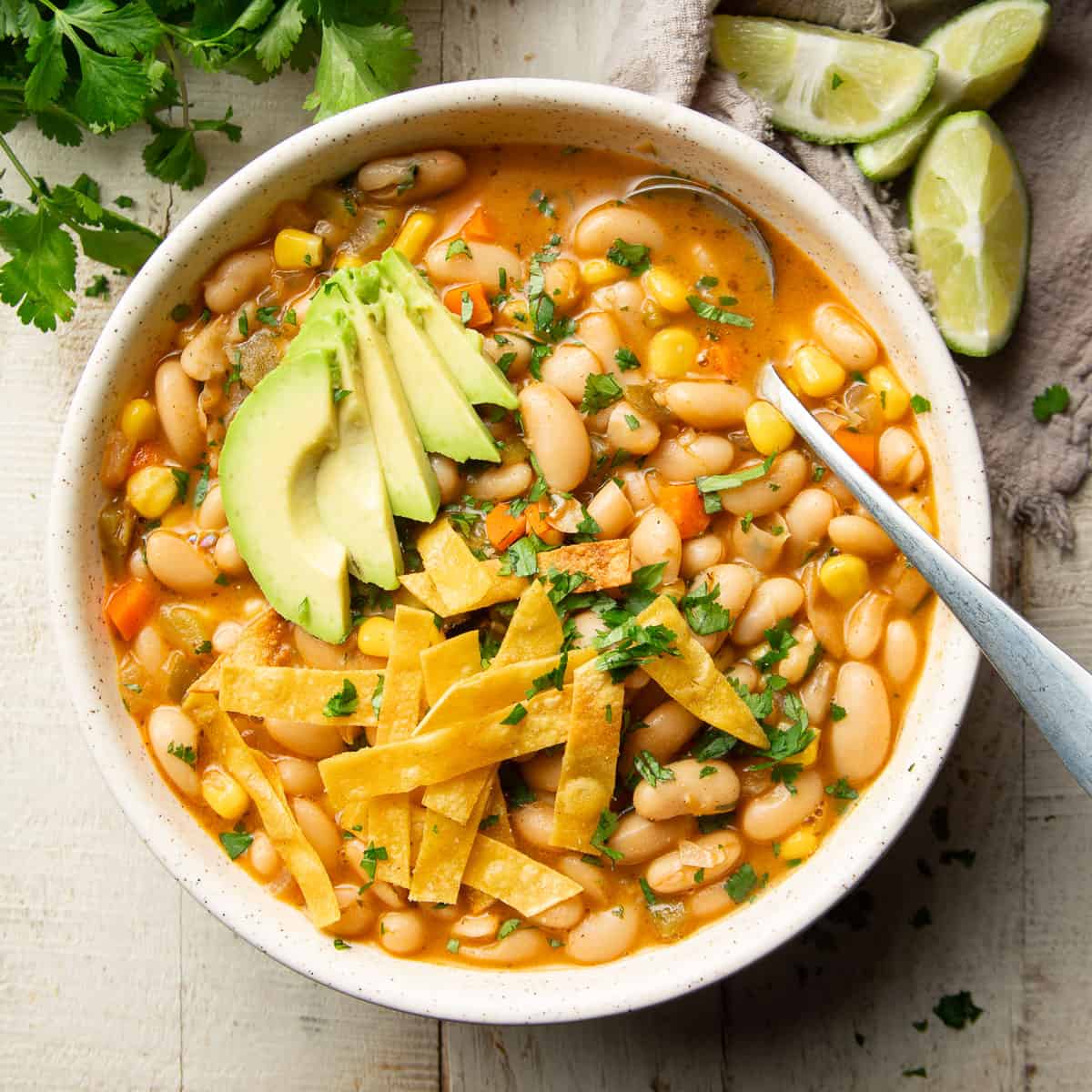 Bowl of Vegan White Bean Chili with avocado and tortilla strips on top.