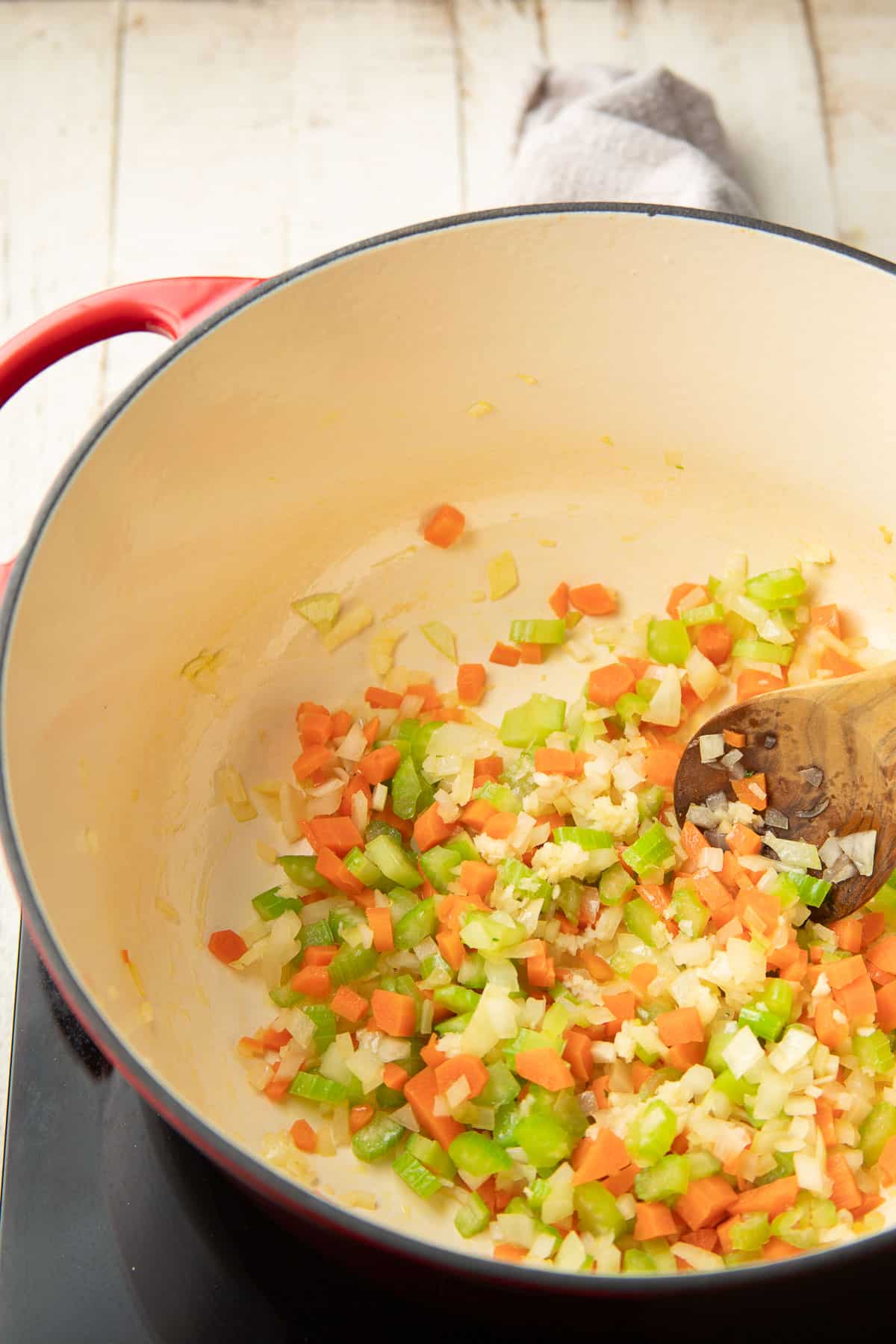 Chopped celery, carrots, onion, and garlic cooking in a pot.