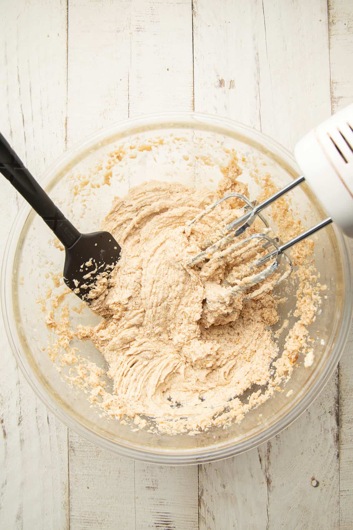 Mixture of vegan butter, sugar and flax egg with electric mixer and spatula.