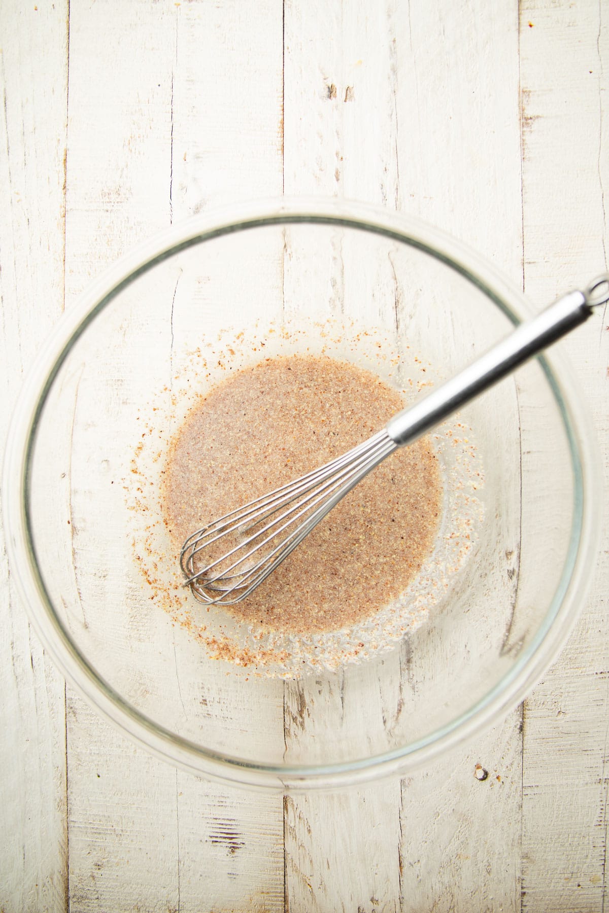 Ground flaxseeds and water in a mixing bowl with a wire whisk.
