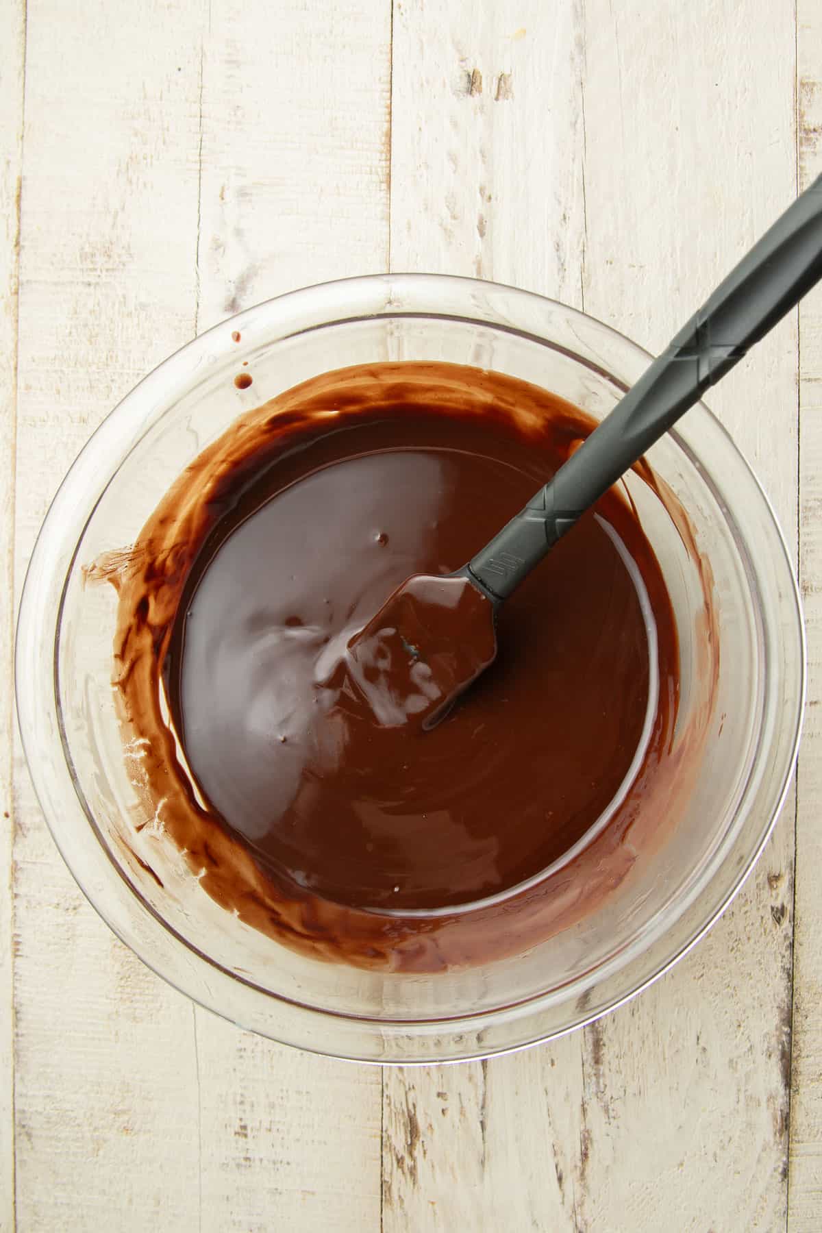 Melted chocolate in a mixing bowl with spatula.