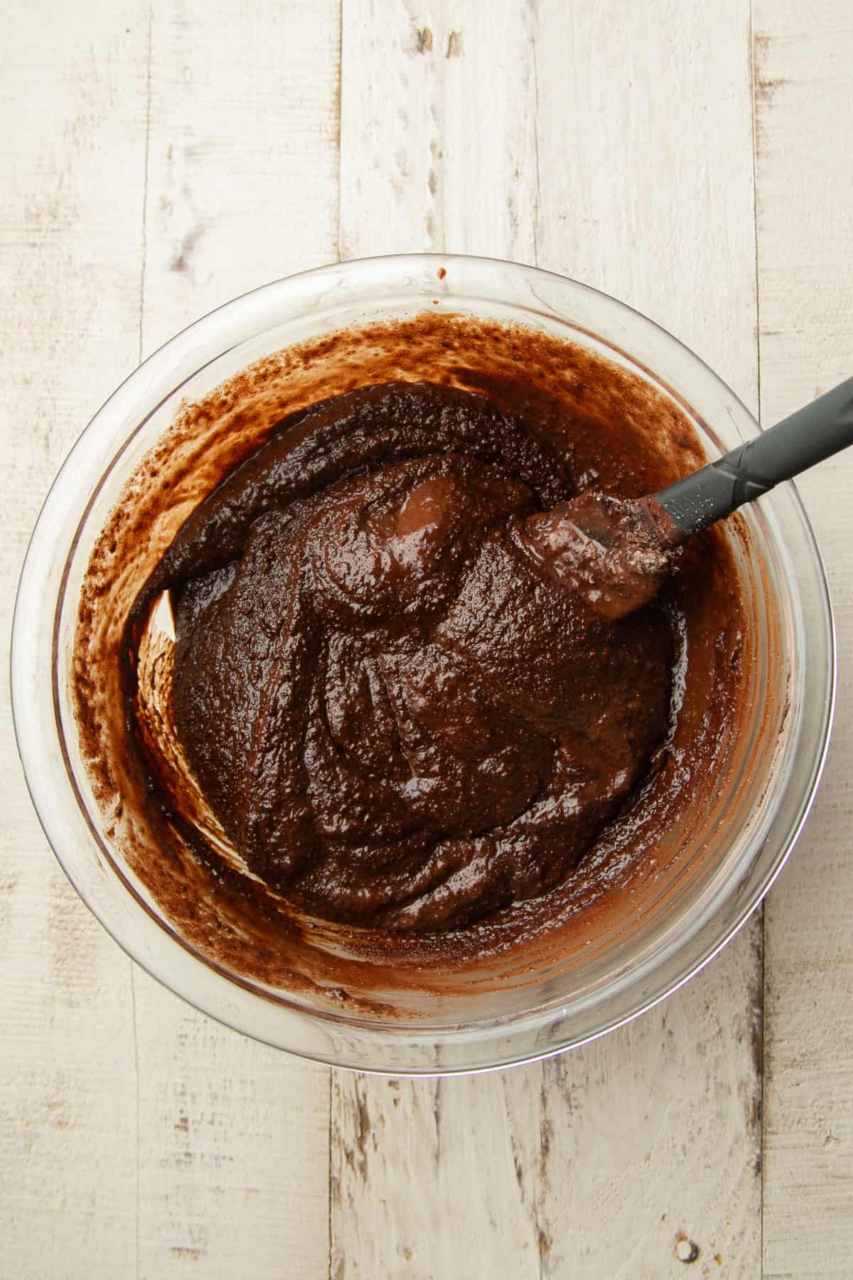 Mix of chocolate, almond flour and wet ingredients for vegan torte batter in a mixing bowl.