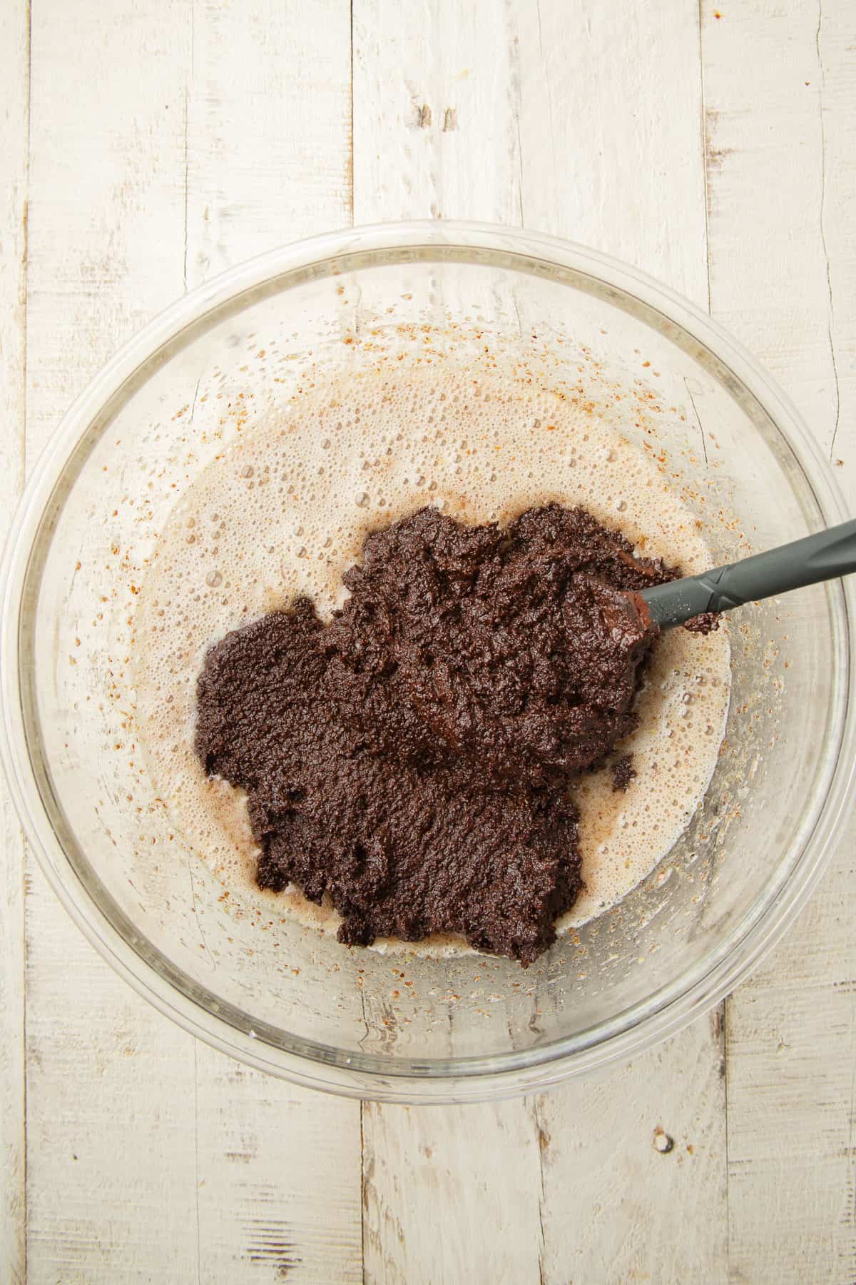 Whipped flax eggs in a mixing bowl with mixture of almond flour and cholate on top.