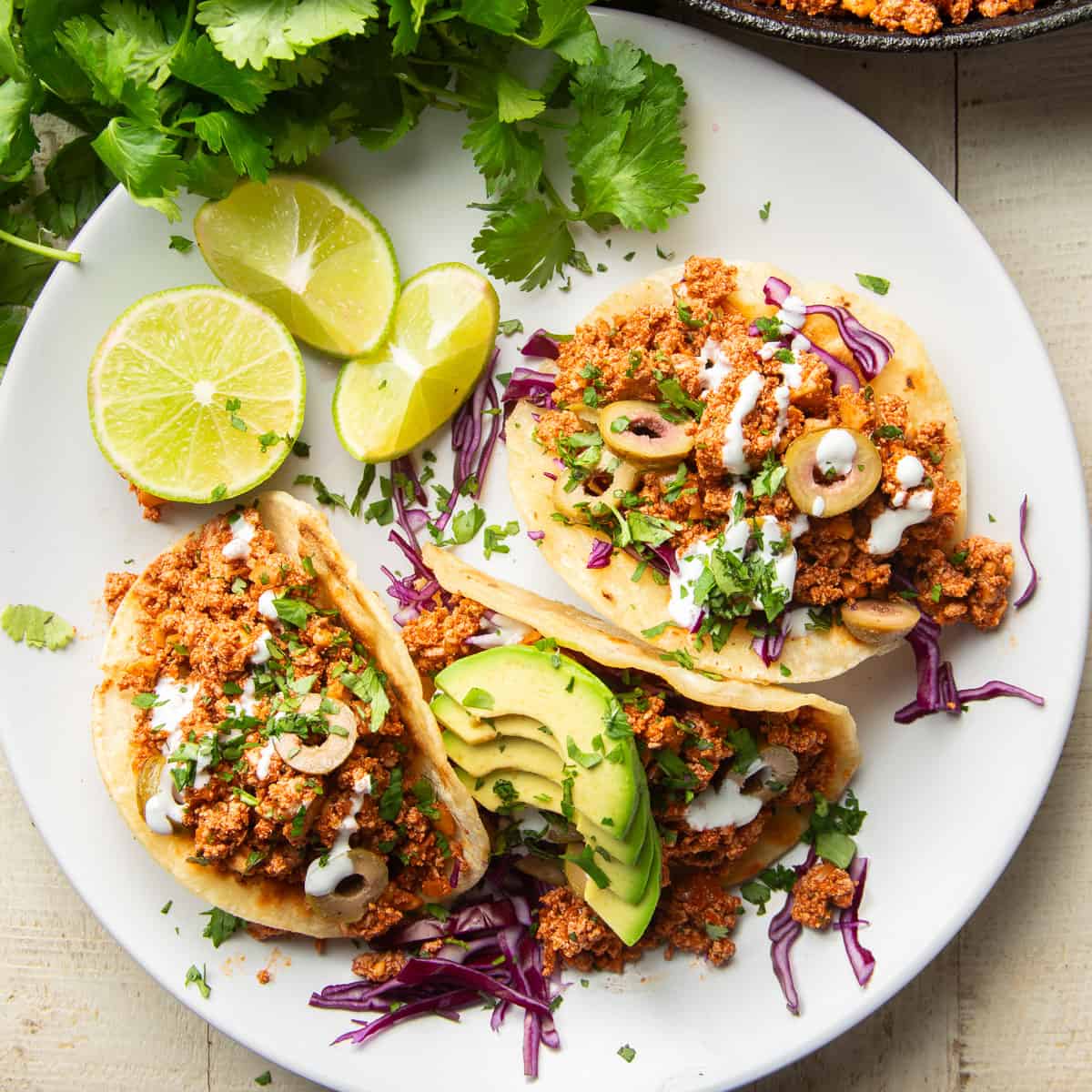 Three Vegan Chorizo Tacos on a plate with lime slices.