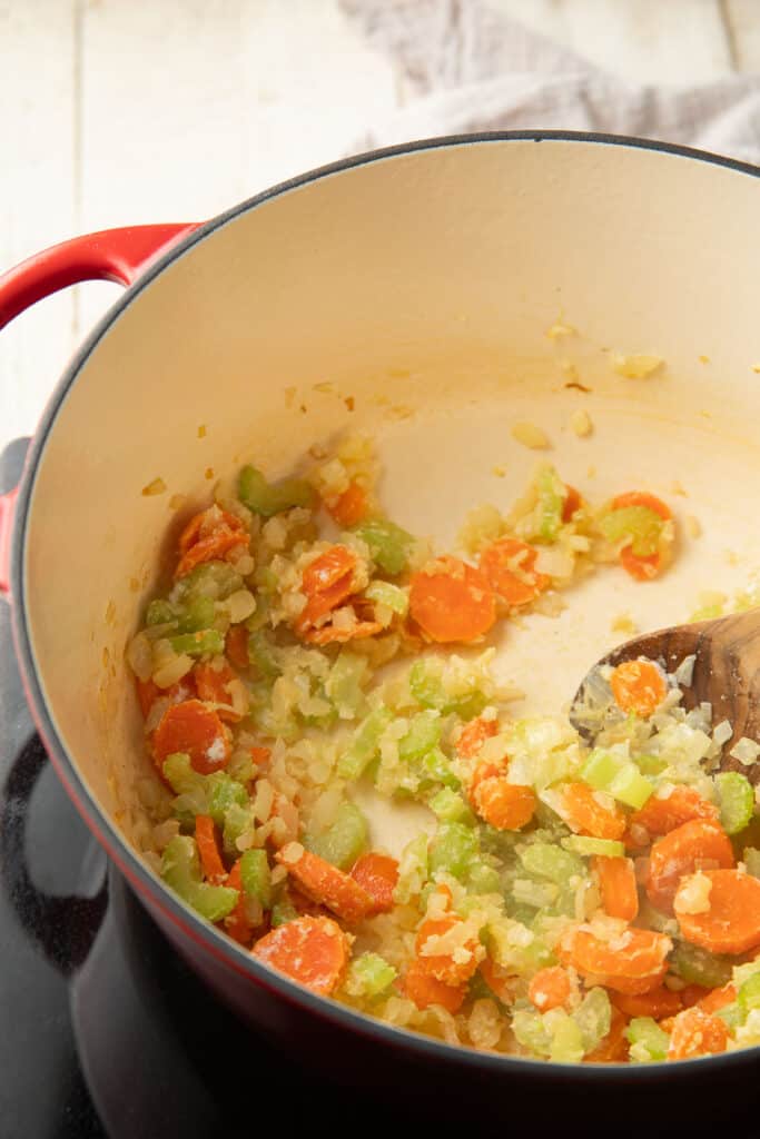 Carrots, onions, celery, and garlic cooking in pot with flour.