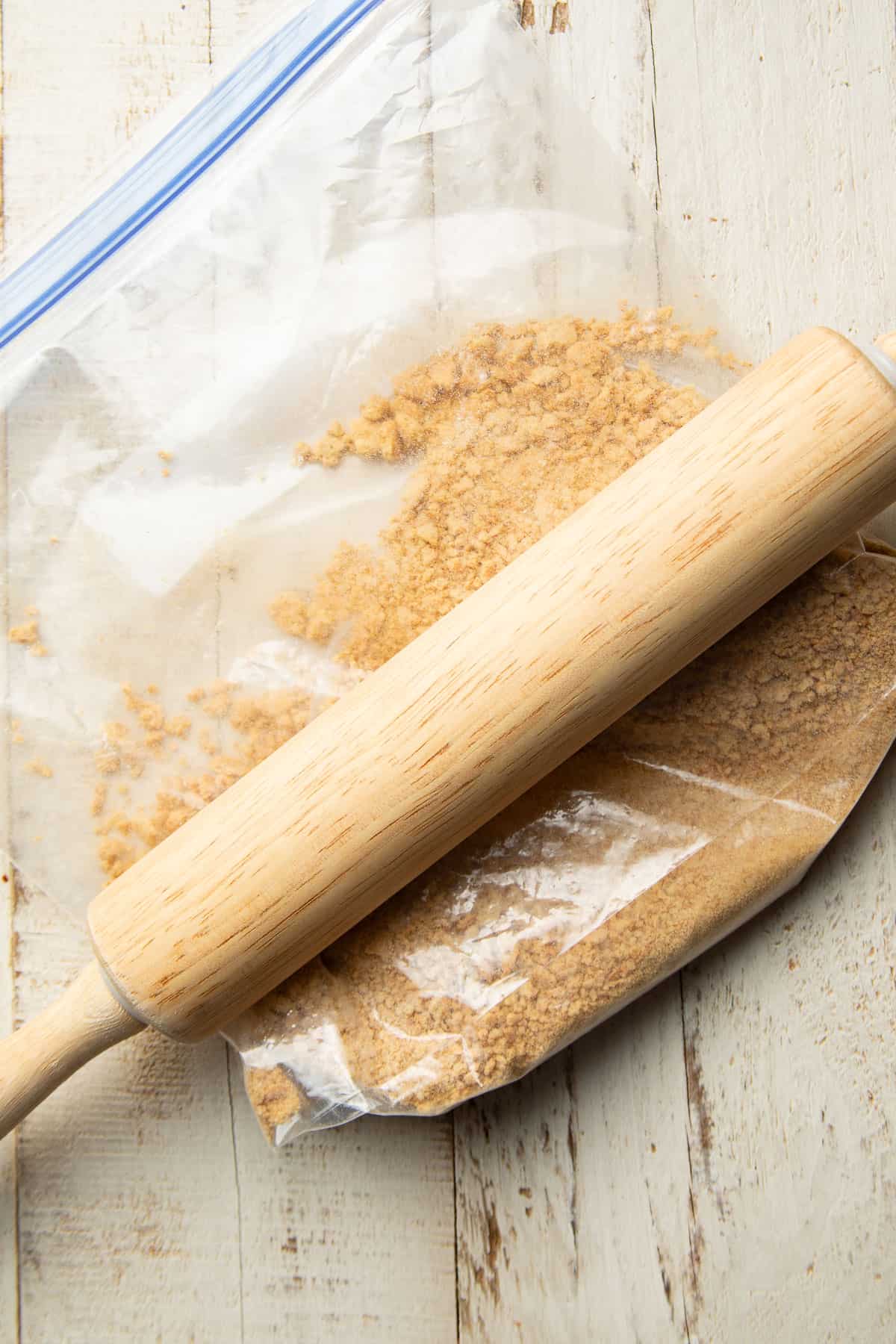 Graham cracker crumbs in a sealed bag with a a rolling pin on top.