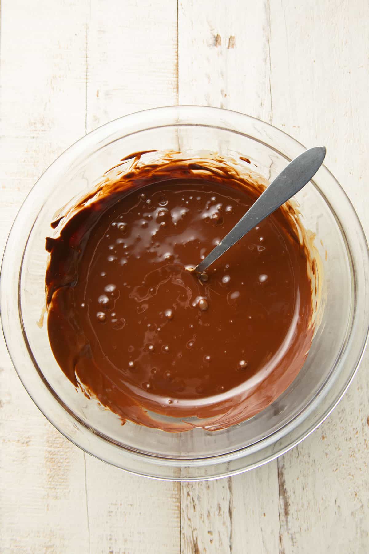Melted chocolate and peanut butter in a glass bowl with spoon.