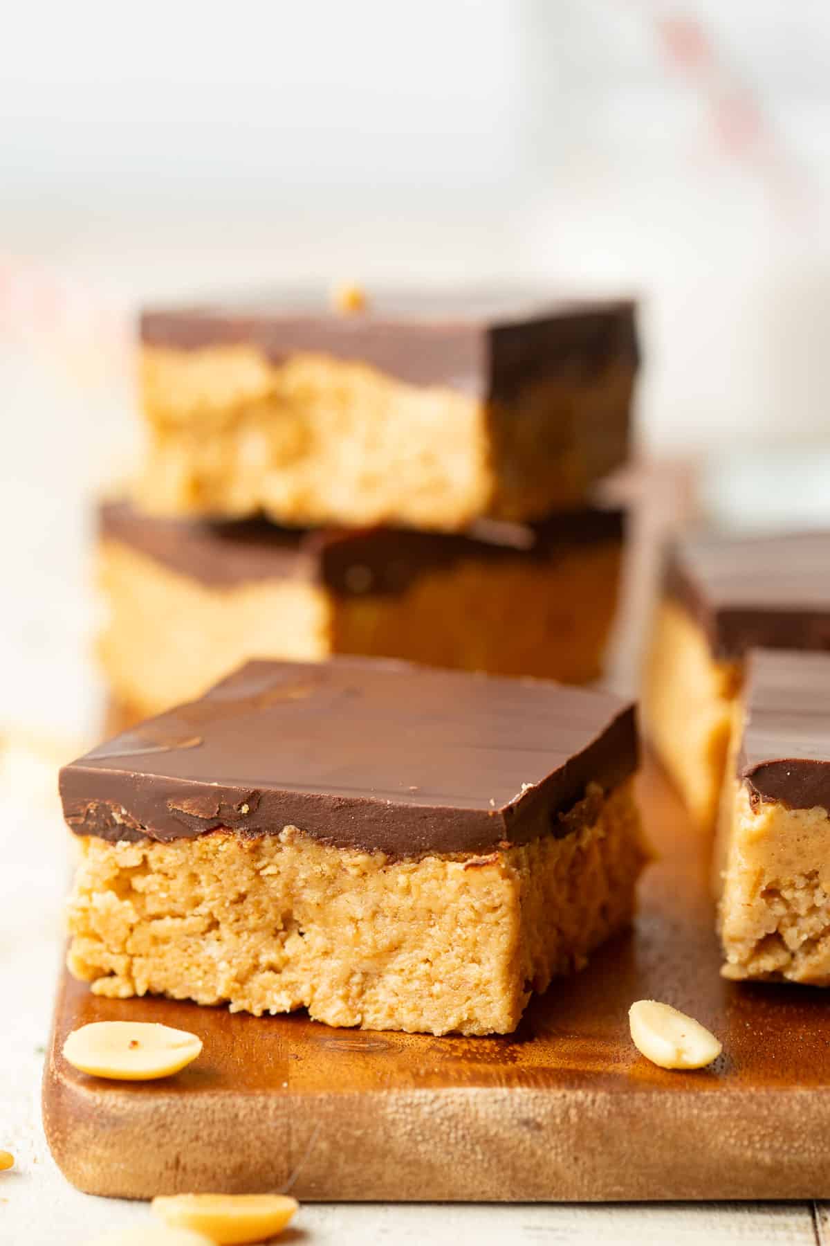Vegan Peanut Butter Bars arranged on a wood surface with scattered peanuts.