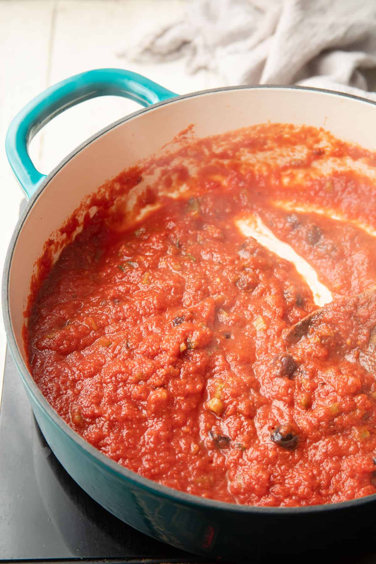 Tomato sauce with olives simmering in a pot.