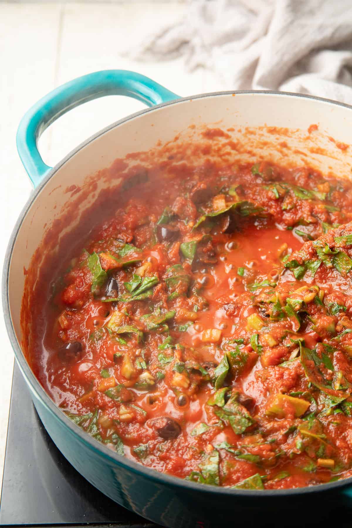 Swiss chard cooking in tomato sauce in a pot.