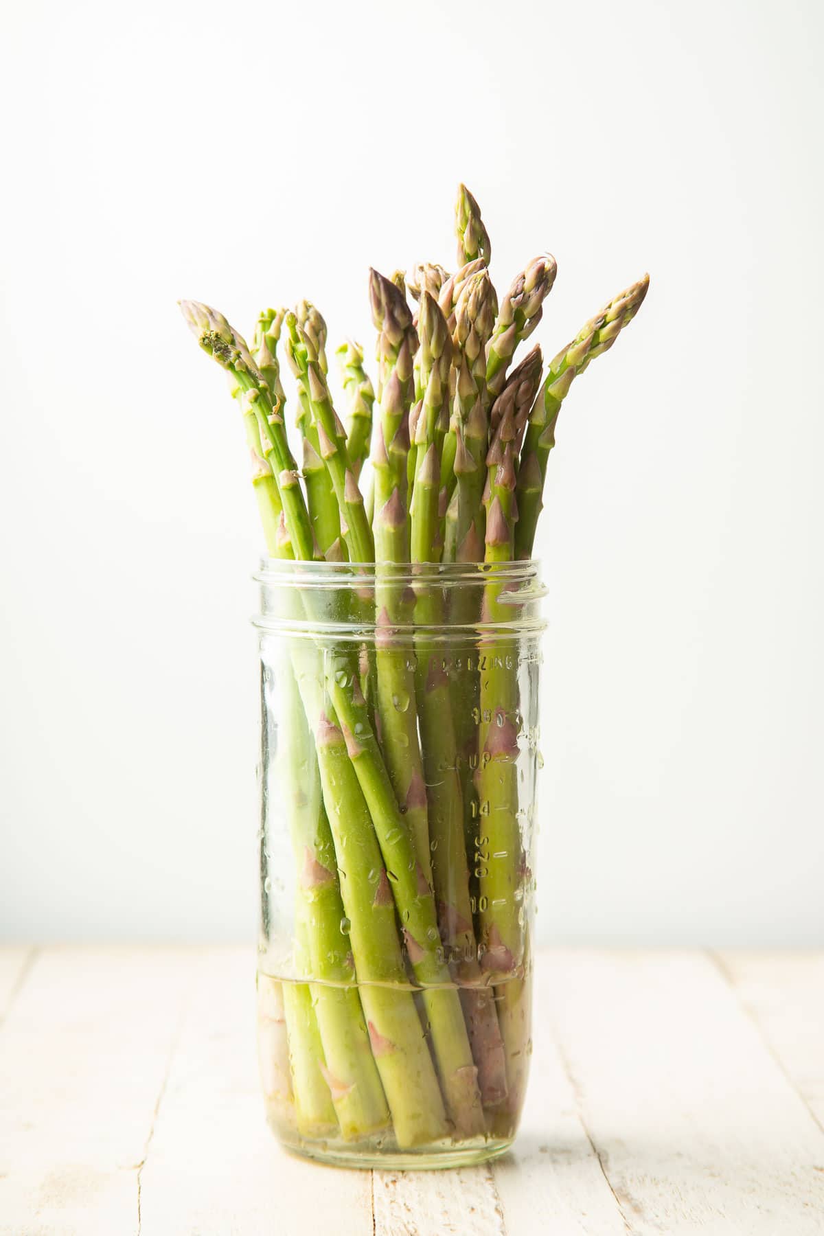 Asparagus spears standing in a jar containing a small amount of water.