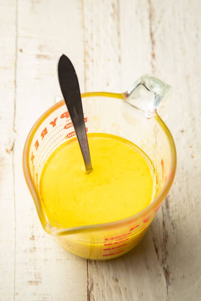 Wet ingredients for Vegan Lemon Loaf in a liquid measuring cup with spoon,