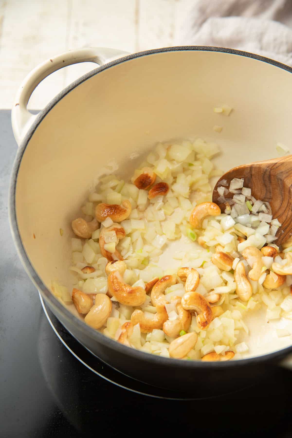 Diced onions and cashews cooking in a pot.