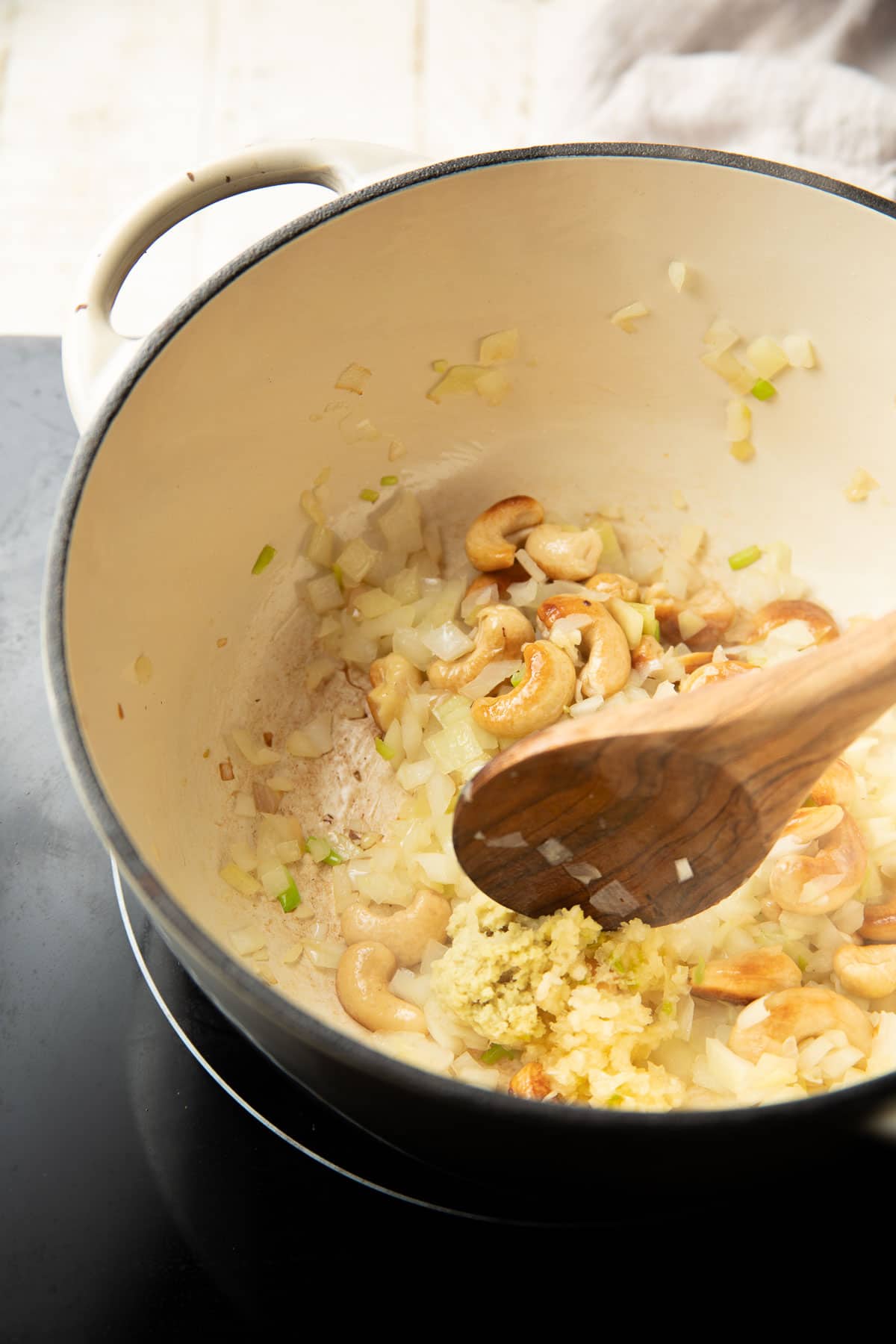Ginger and garlic cooking in a pot with cashews and diced onions.