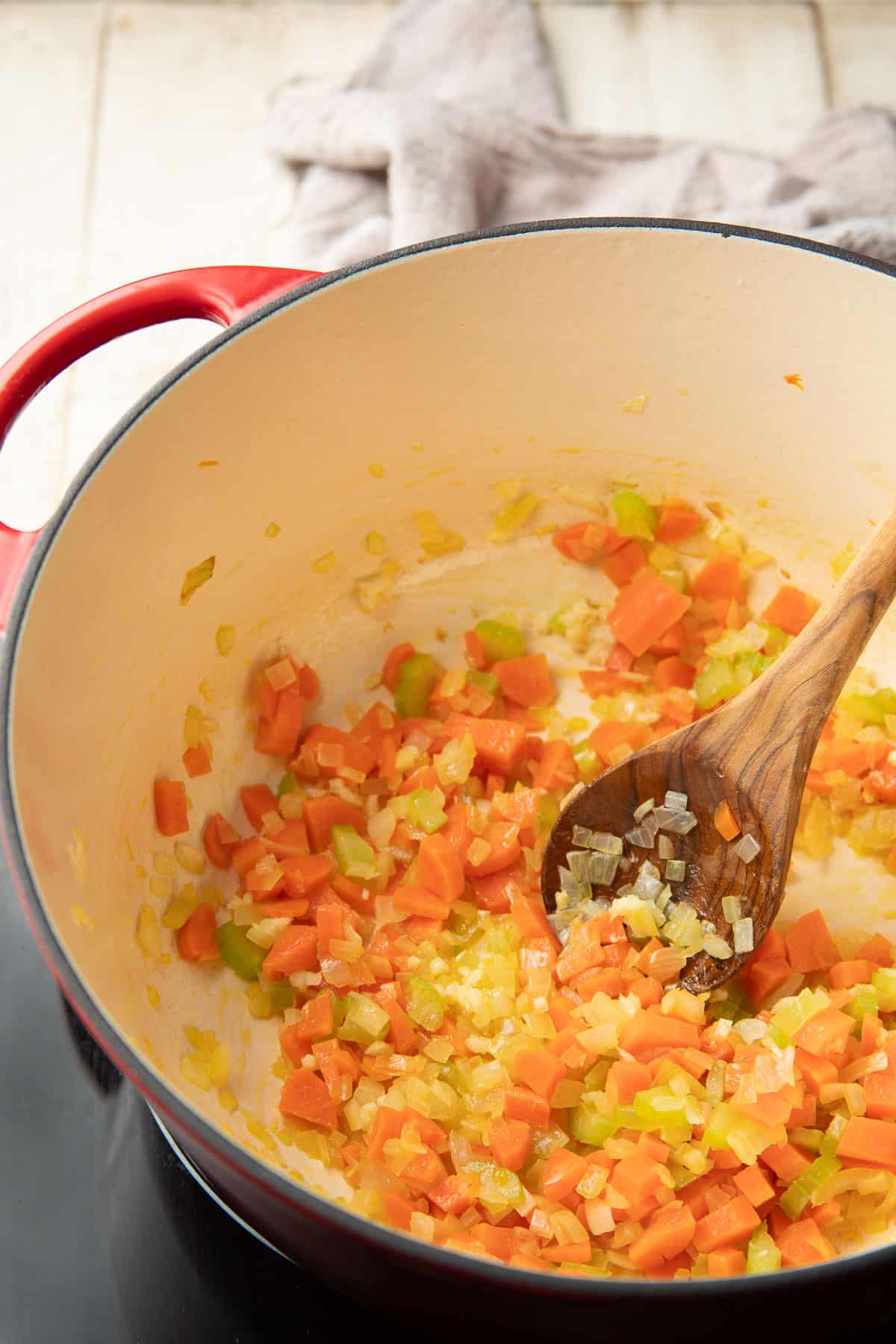 Diced carrots, celery, onion, and minced garlic cooking in a pot.