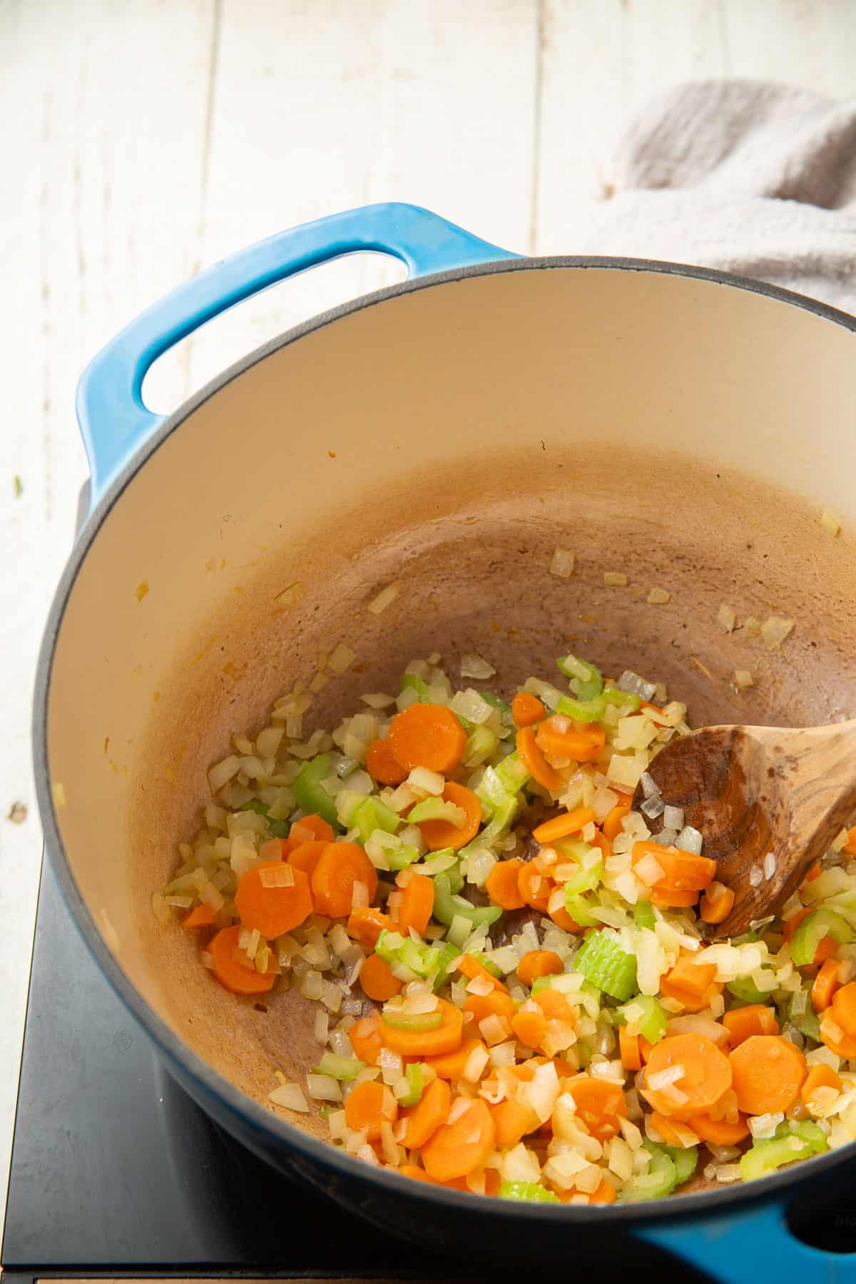 Onion, celery, and carrots cooking in a pot.