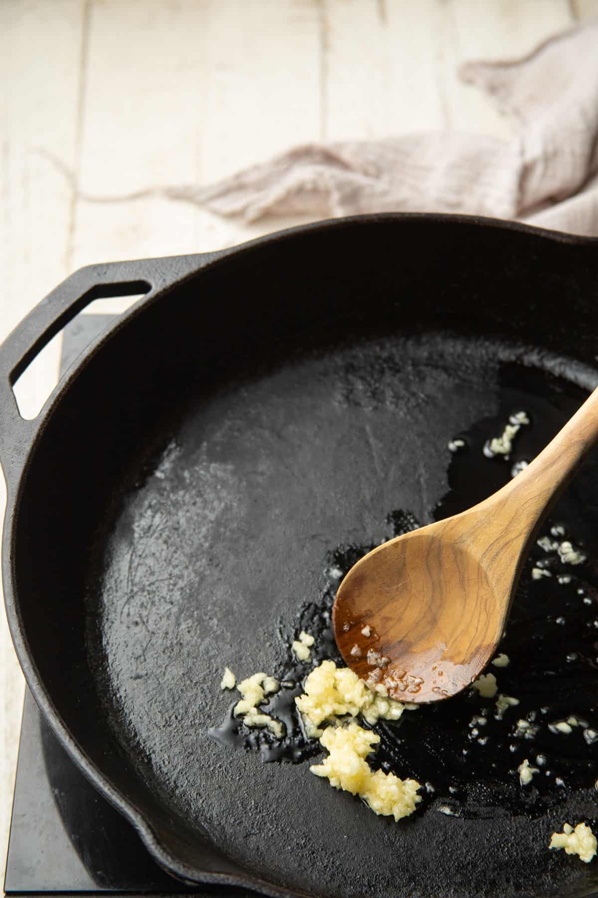 Minced garlic cooking in olive oil in a skillet.