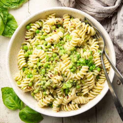 Bowl of pasta and peas with a fork and spoon.