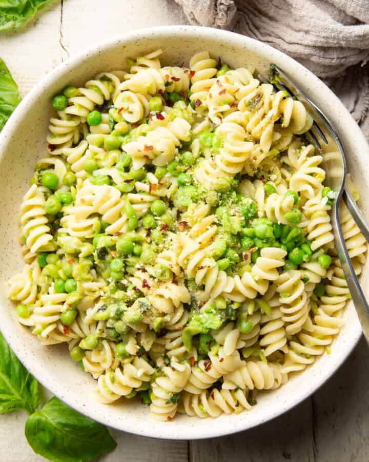 Bowl of pasta and peas with a fork and spoon.