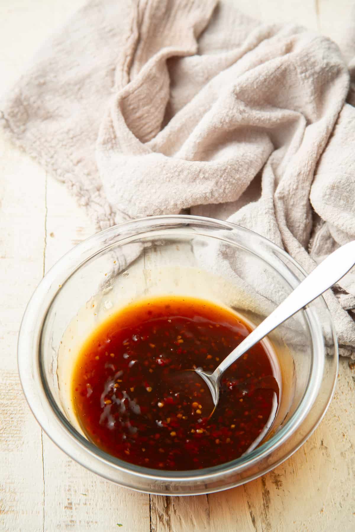 Bowl containing a mixture of sweet chili sauce and soy sauce with a spoon.
