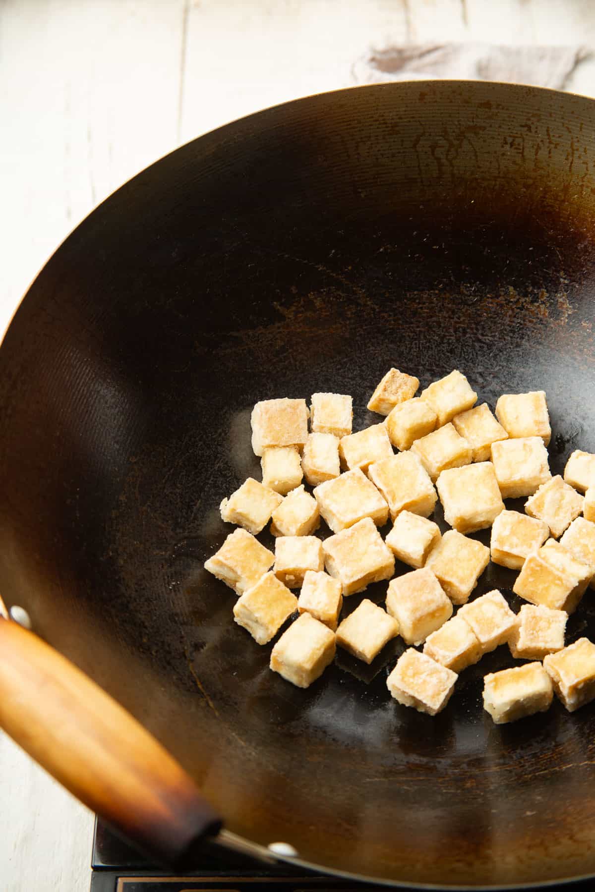 Tofu cubes frying in a wok.