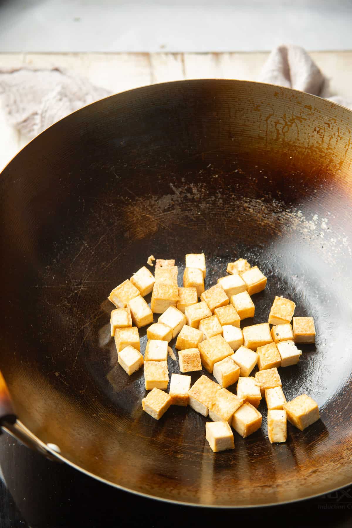 Tofu cubes cooking in a wok.