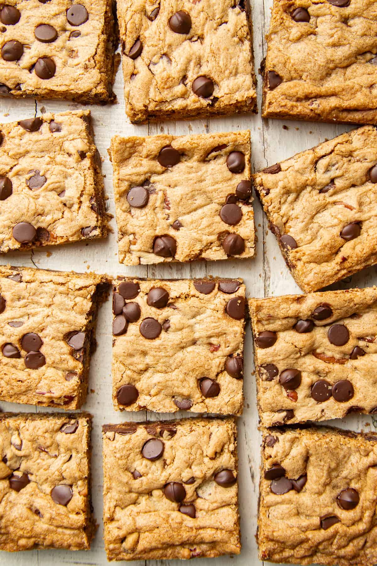Vegan Chocolate Chip Cookie Bars arranged on a white wooden surface,