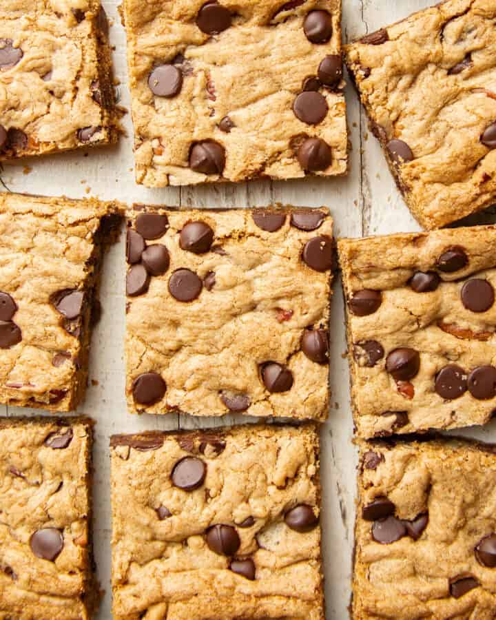 Vegan Chocolate Chip Cookie Bars arranged on a white wooden surface.