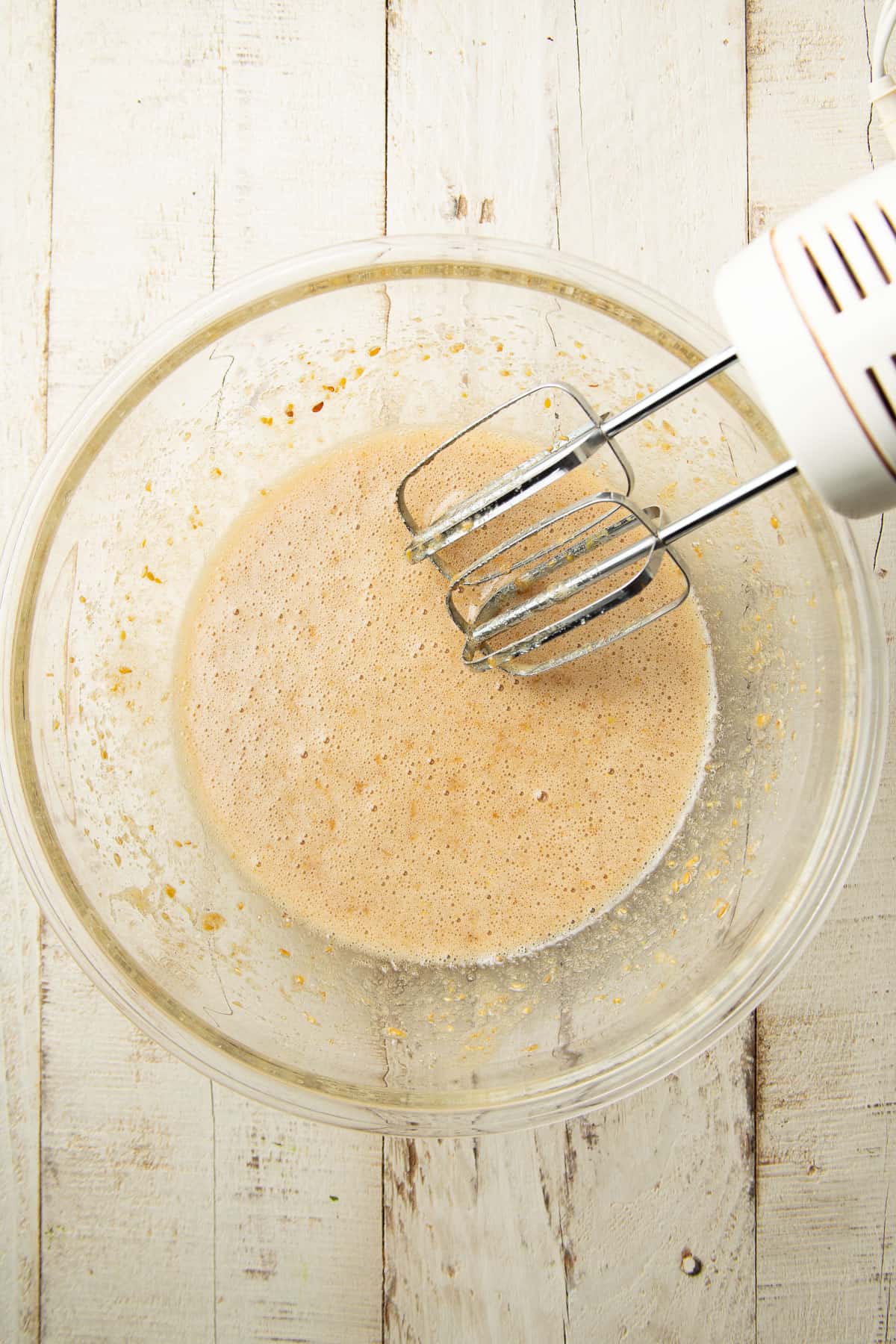 Flax egg blended with sugar in a mixing bowl with an electric mixer.