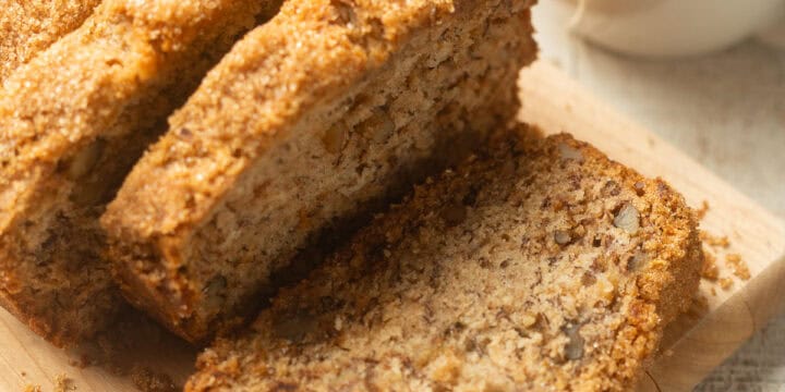Sliced loaf of Vegan Banana Bread with a cup of tea in the background.