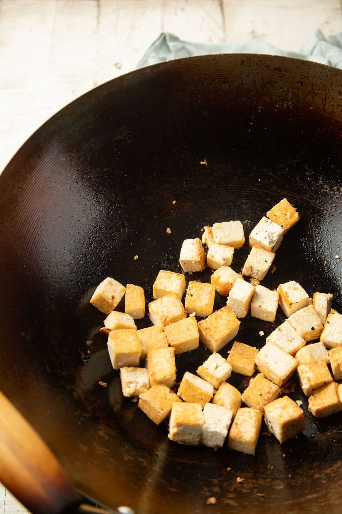 Tofu cubes cooking in a wok.