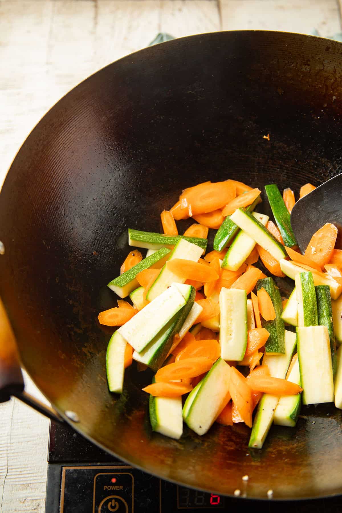 Carrots and zucchini stir-frying in a wok.