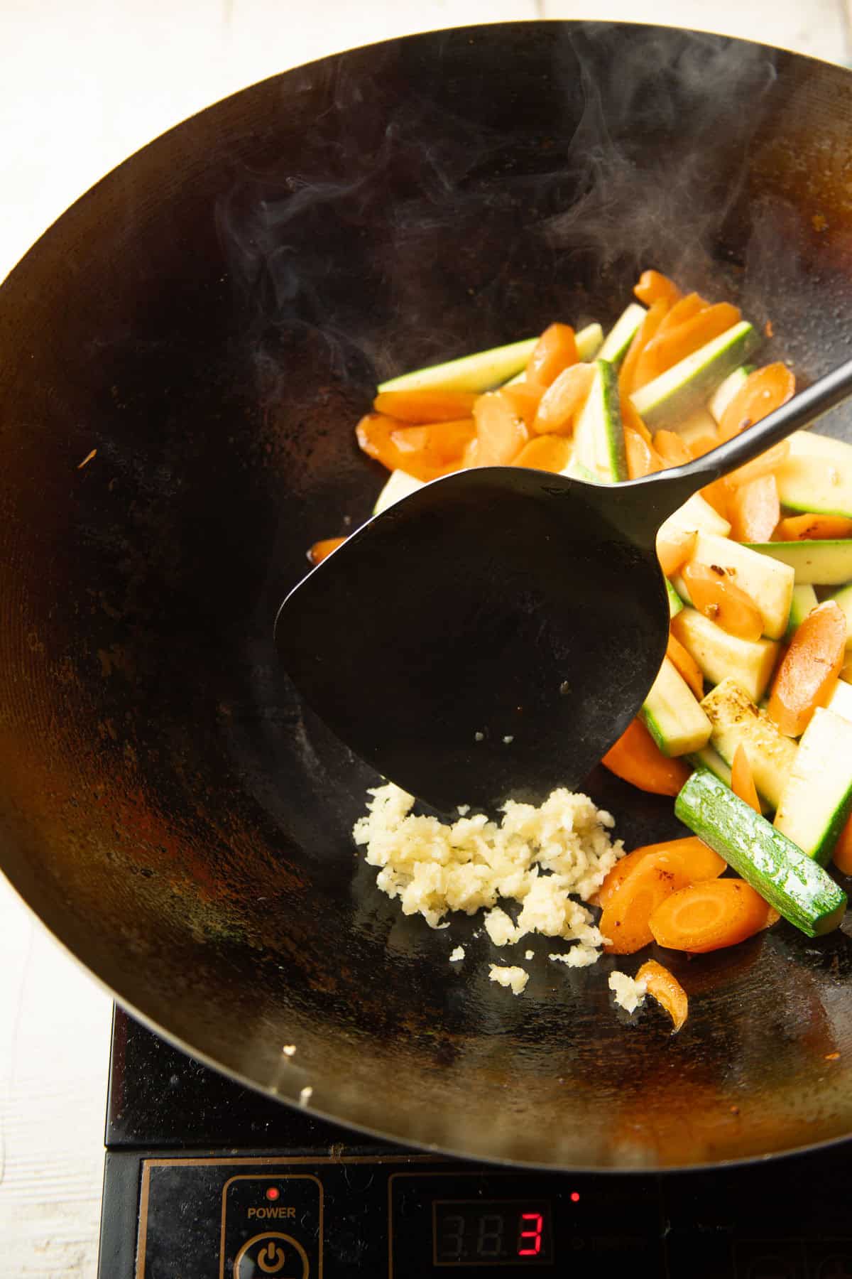 Minced garlic cooking in a wok with vegetables.