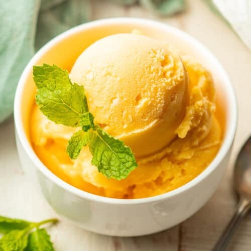 Bowl of Mango Sorbet garnished with mint leaves.