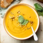 Bowl of Slow Cooker Butternut Squash Soup topped with sage leaves, pepitas, and olive oil.
