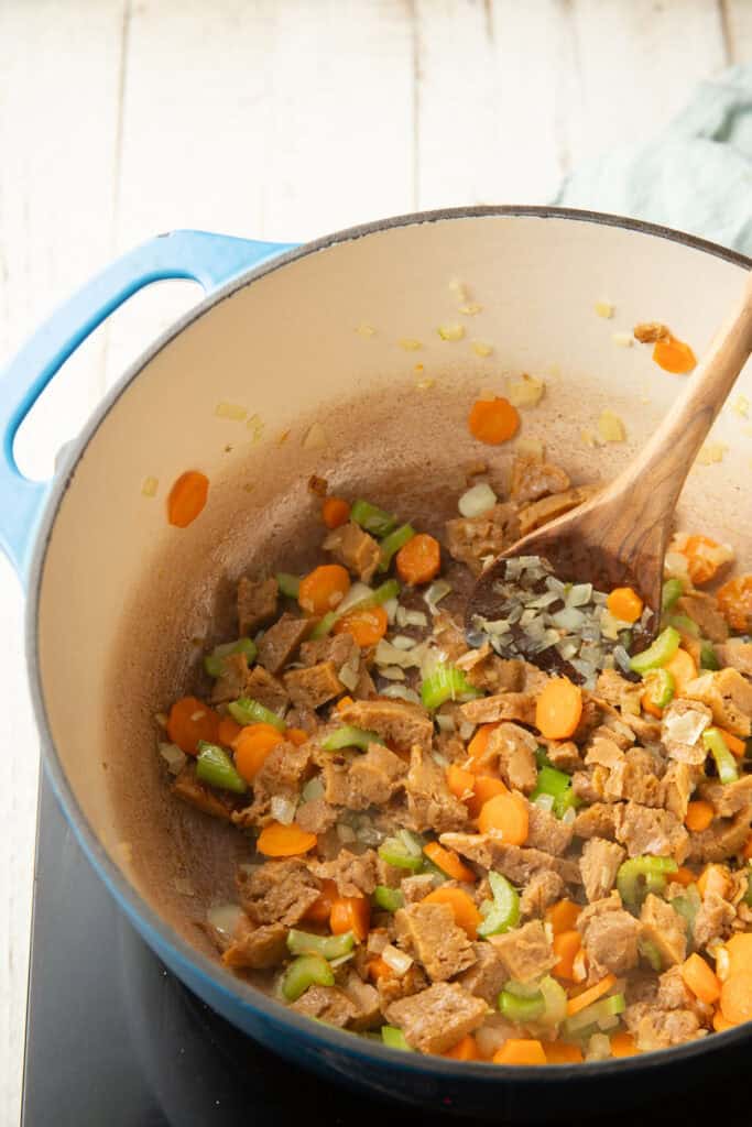 Seitan, carrots, celery, and onions cooking in a pot.