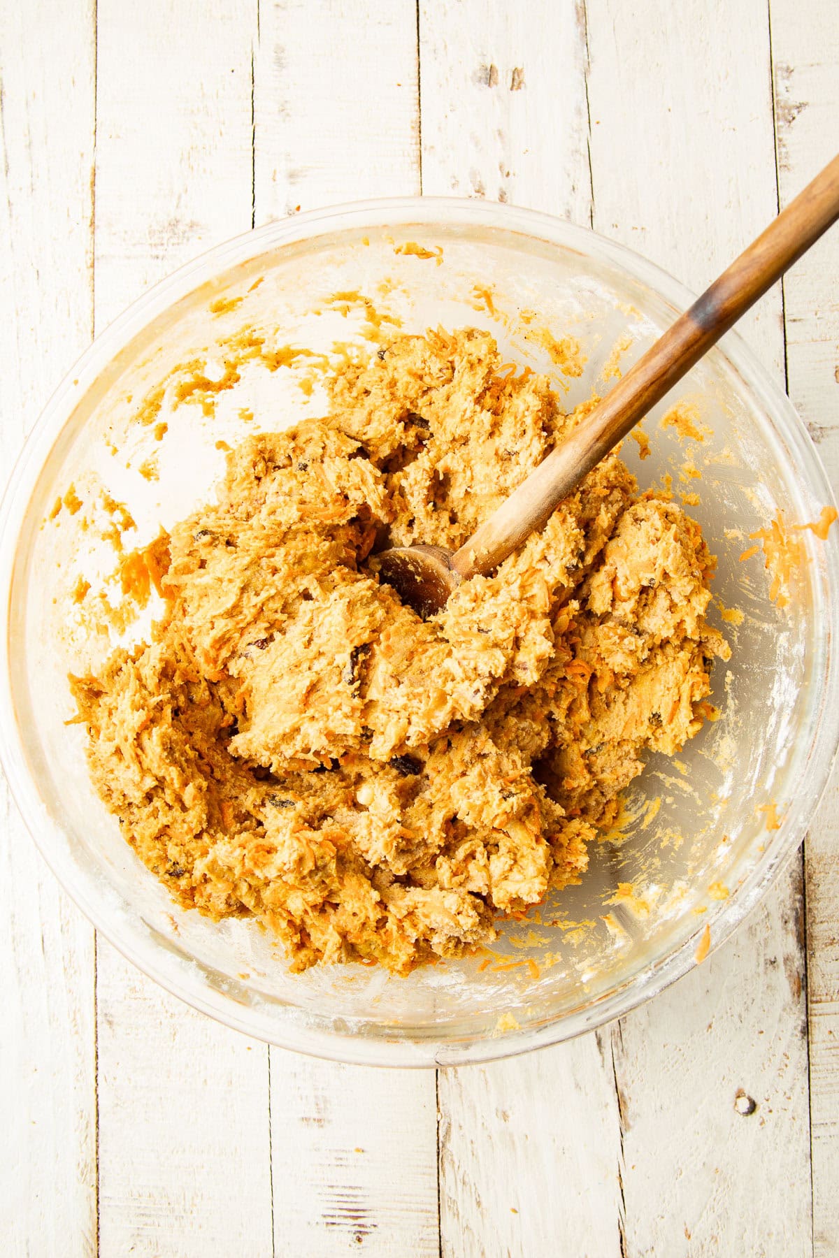 Vegan Carrot Cake Cookie dough in a mixing bowl with wooden spoon.
