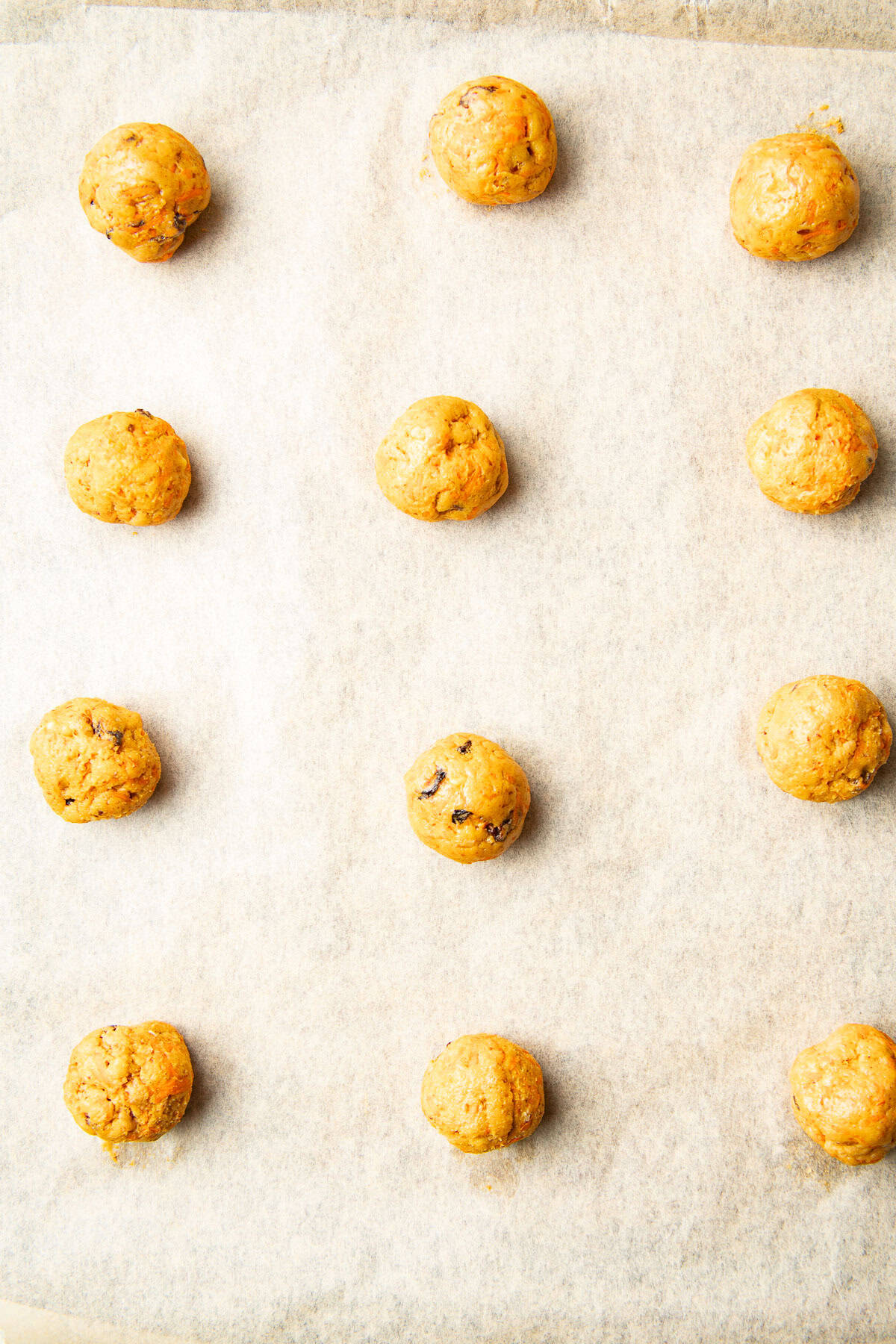 Cookie dough balls on a parchment paper-lined baking sheet.