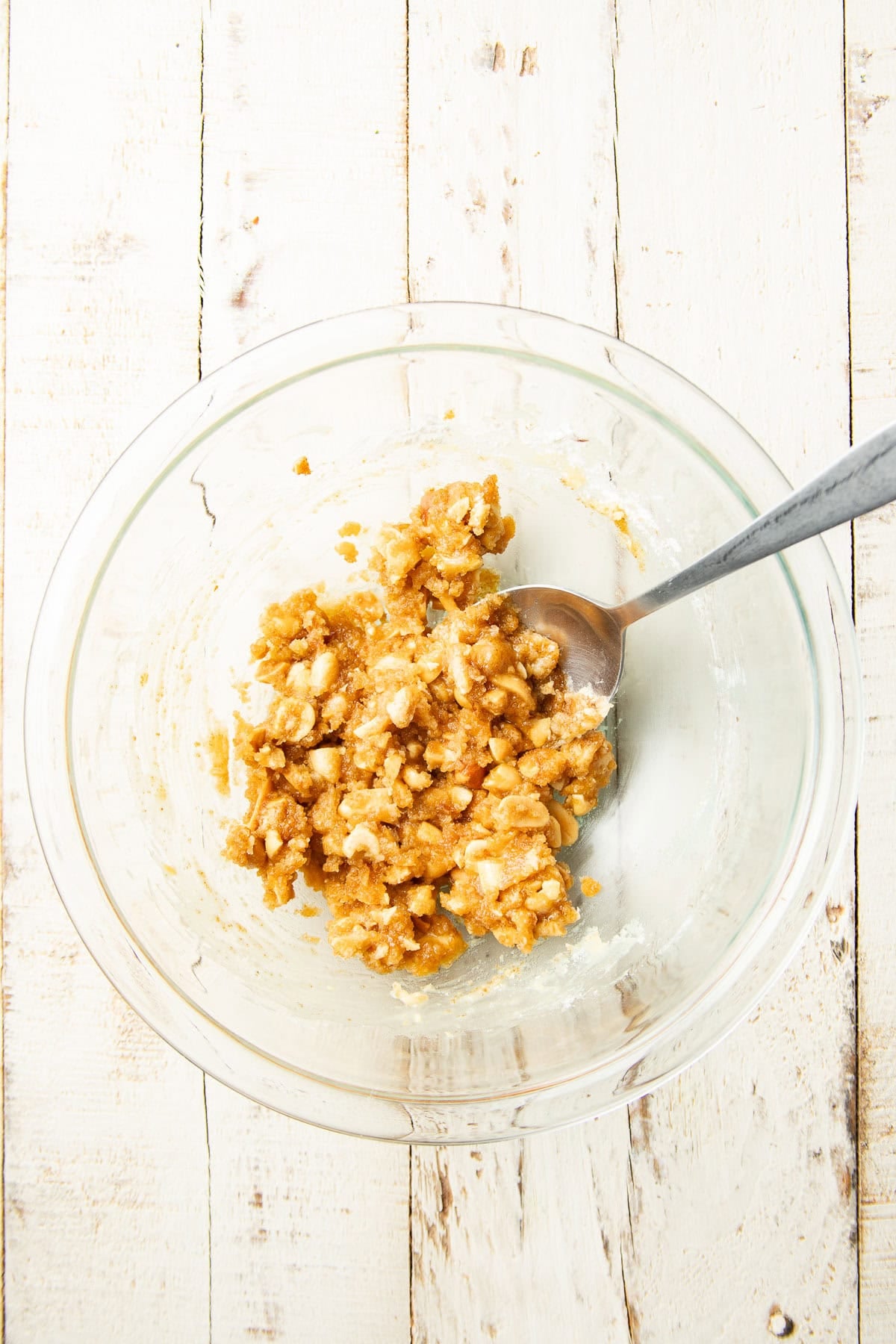 Peanut crumb topping mixture in a bowl with spoon.