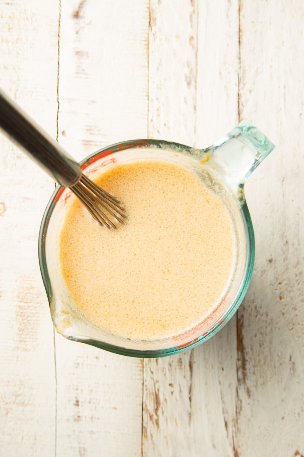 Liquid ingredients for Peanut Butter Bread in a liquid measuring cup with wire whisk.
