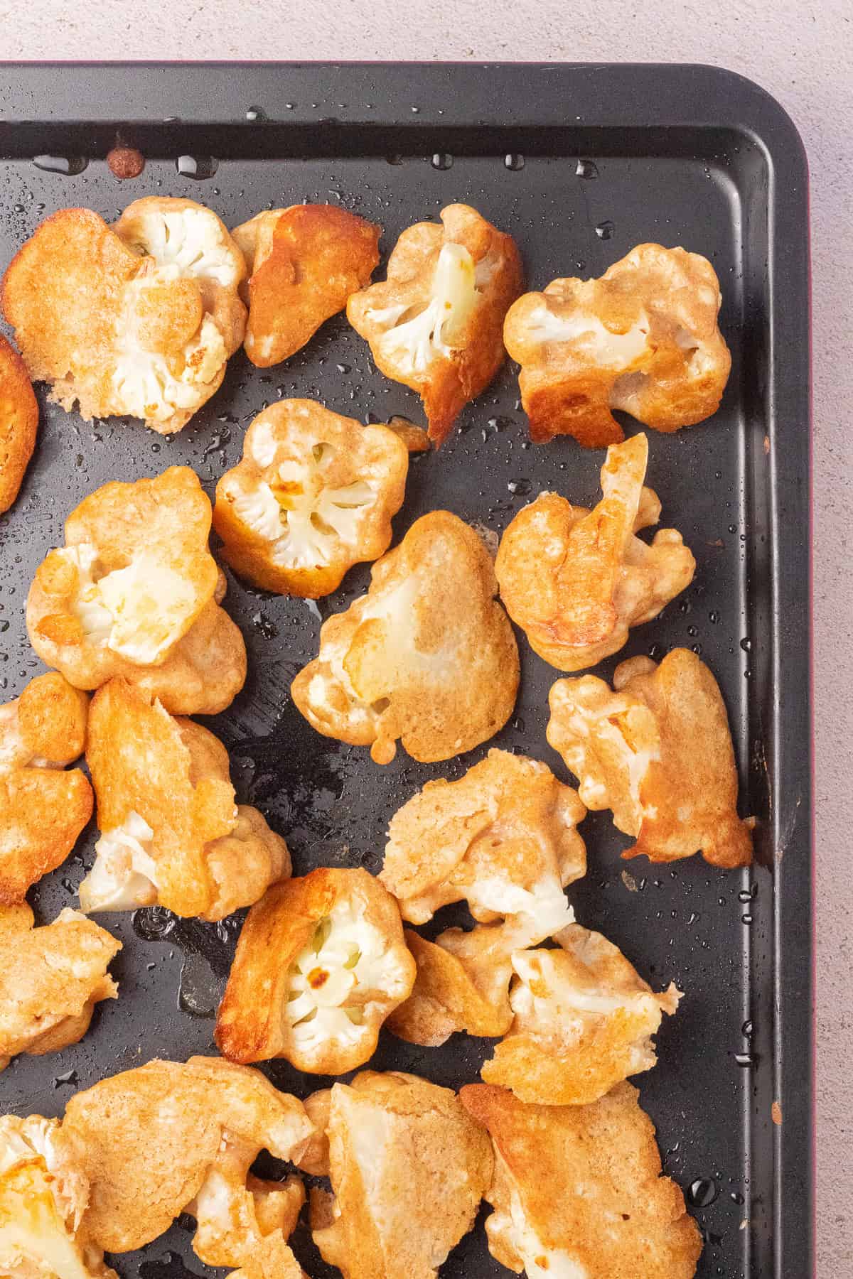 Battered baked cauliflower on a baking sheet.