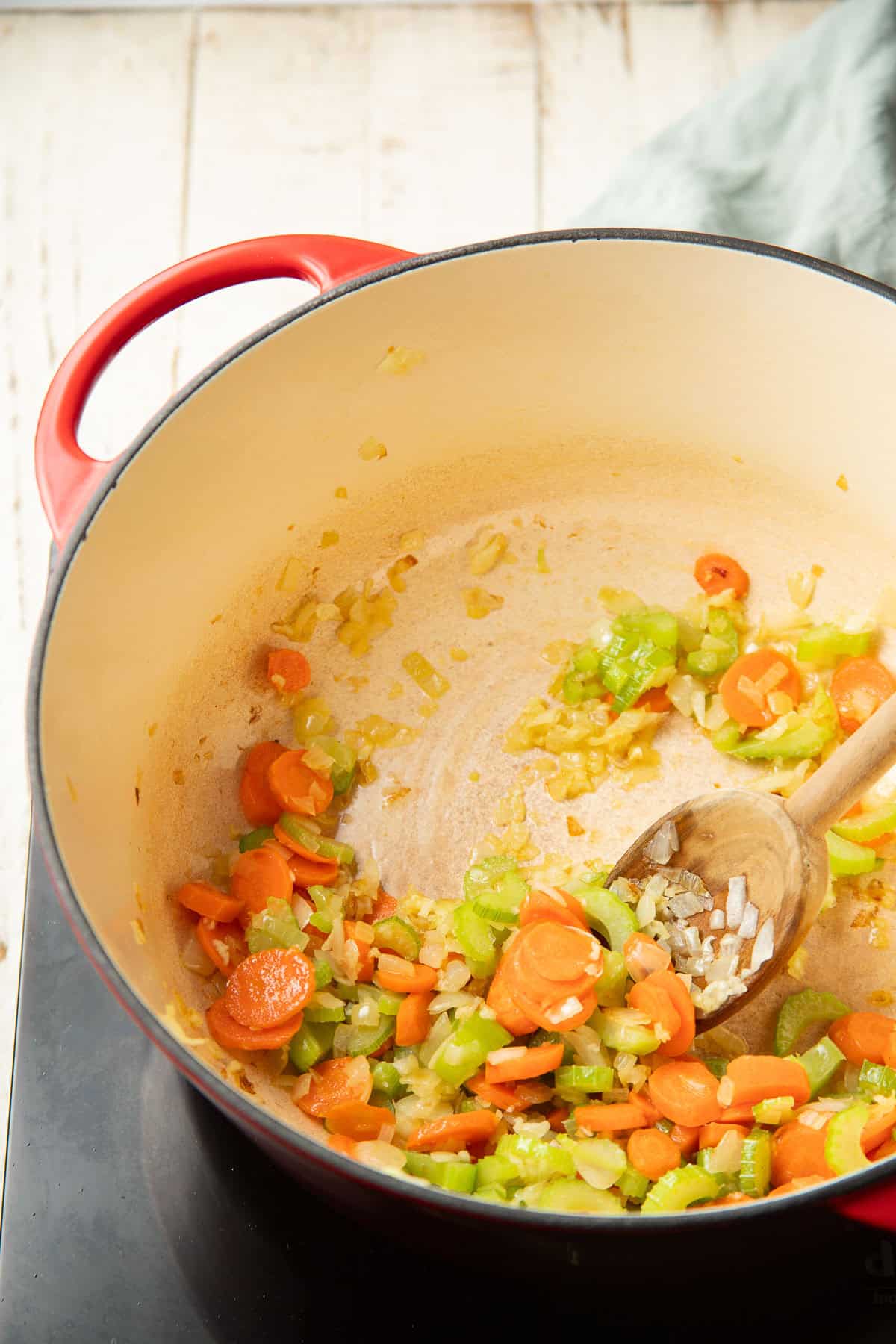 Carrots, celery, onion, and garlic cooking in a pot.